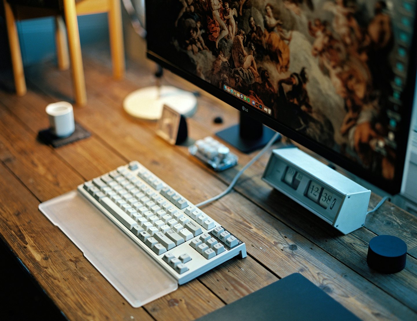 Computer monitor and mechanical keyboard sitting on a wooden desk.